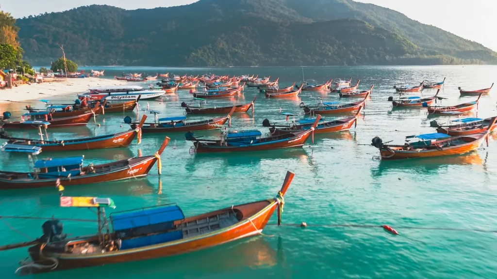 Thai Longtail Boats Line-up along the shore in turquoise waters