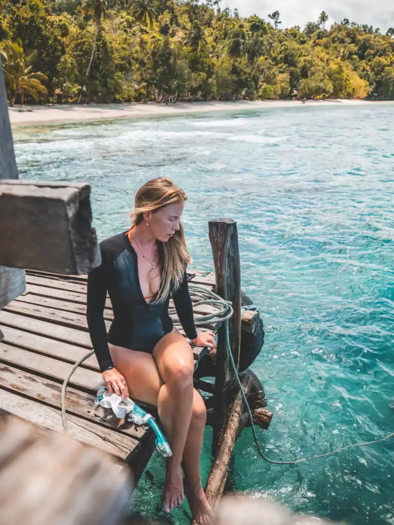 “Snorkeler preparing mask and snorkel before entering water in Raja Ampat