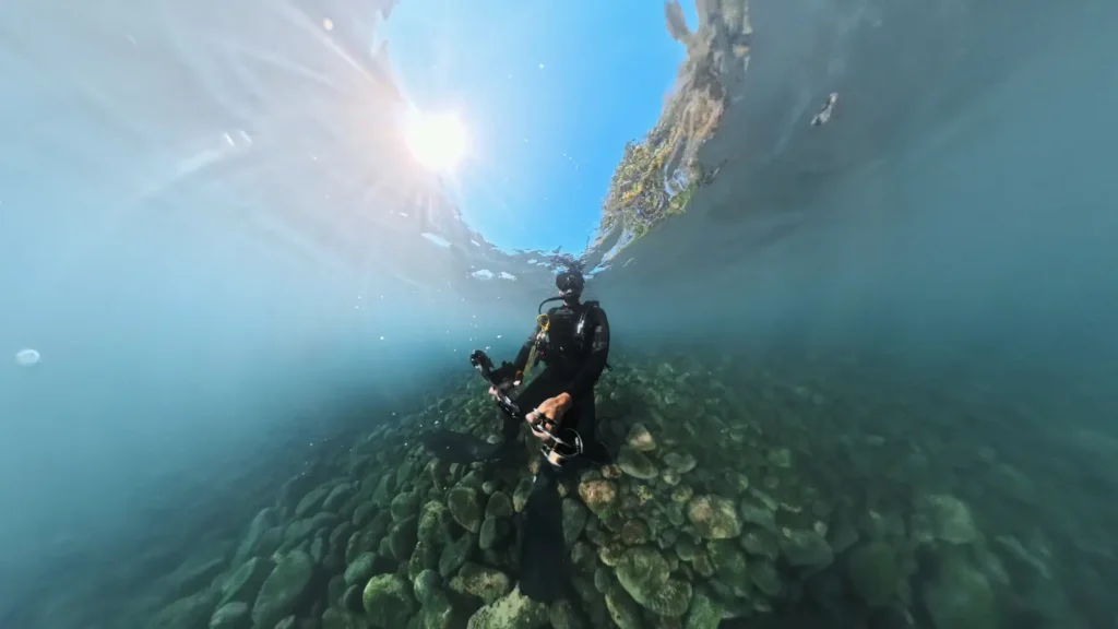 Diver floating above shallow volcanic rocks near the shore at Tulamben, Bali