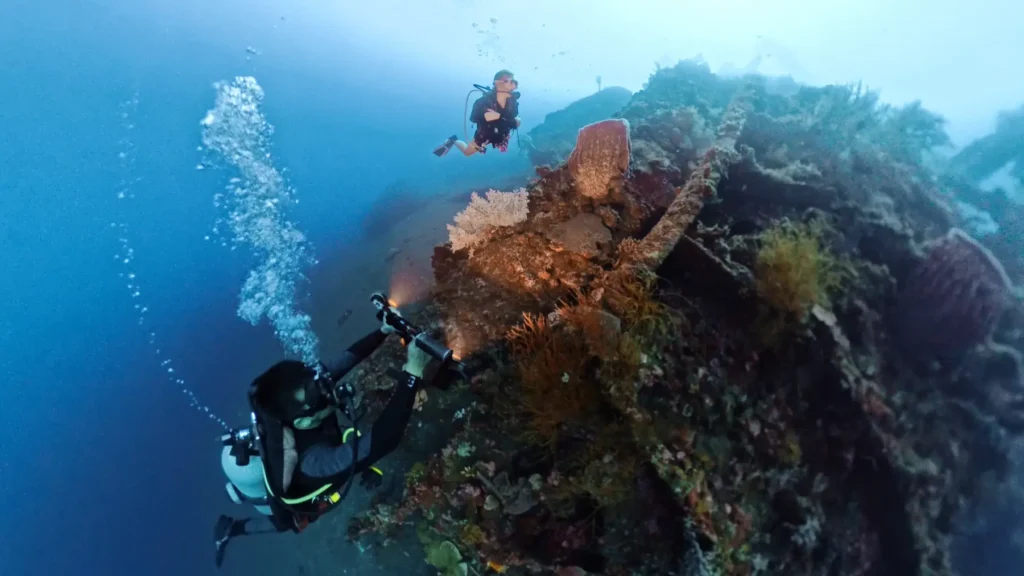 Underwater photographer illuminating coral and wreck structure at the USAT Liberty in Tulamben.