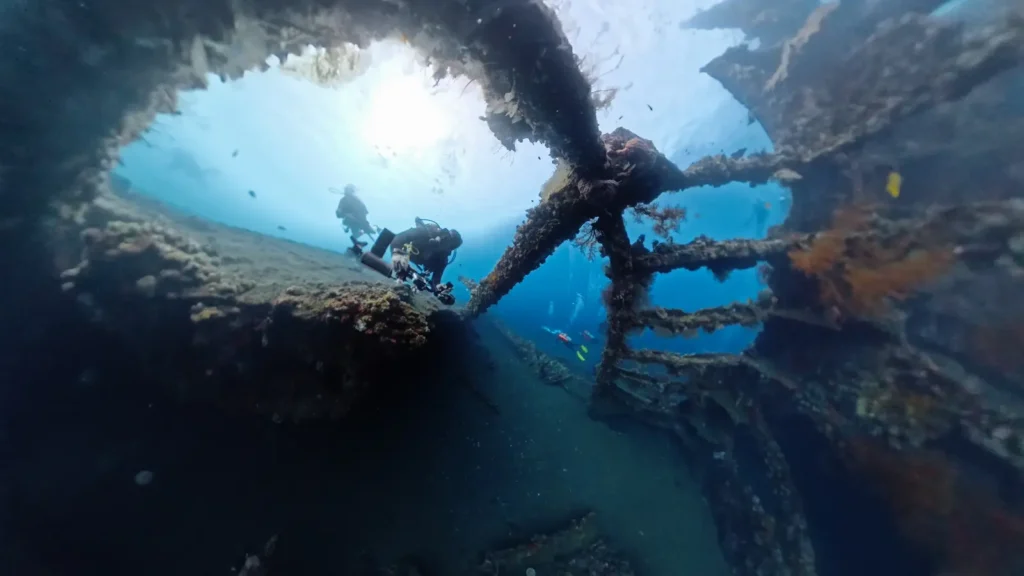Scuba divers exploring the wide rib structures of the USAT Liberty Wreck in Bali.