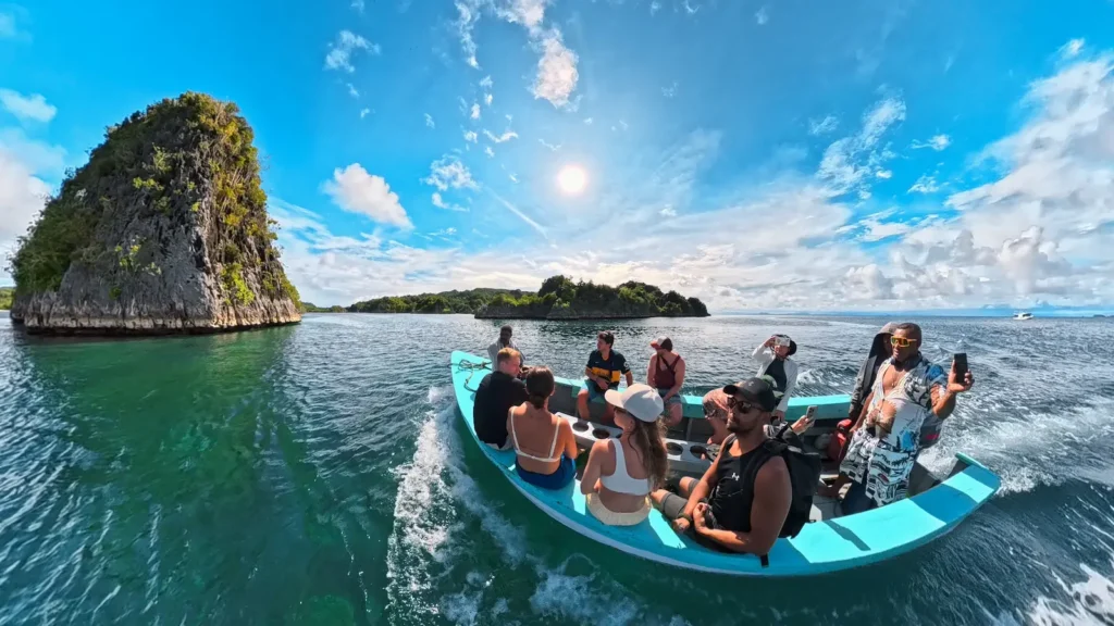 Group of divers on a traditional Raja Ampat dive boat heading out across turquoise water