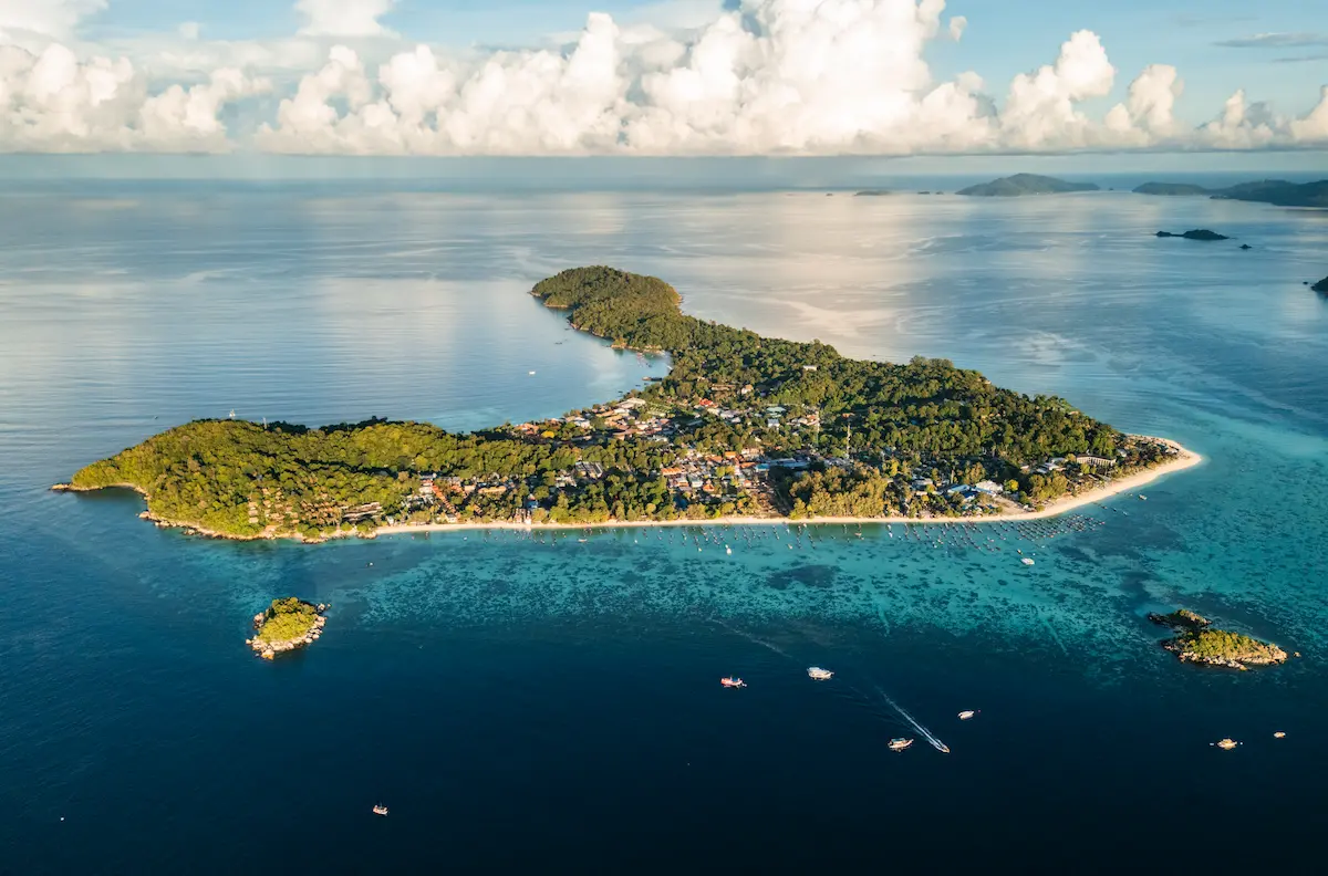 Sunrise Beach Koh Lipe during Thailand rainy season with longtail boats and quiet shoreline
