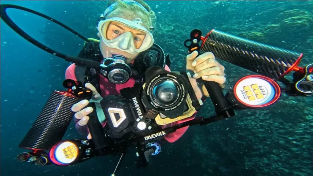 Close-up of an underwater camera housing mounted on a dual-handle tray with two video lights and carbon-fibre float arms